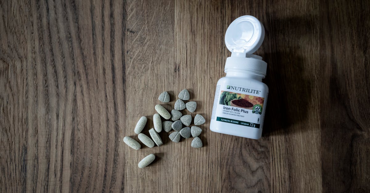 Home Open bottle of Iron Folic Plus tablets with scattered pills on a wooden surface.